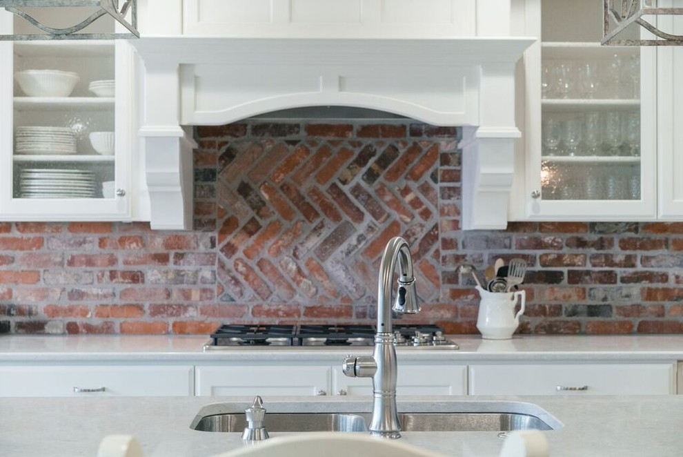 Example of a huge l-shaped light wood floor and brown floor open concept kitchen design with a double-bowl sink, recessed-panel cabinets, brick backsplash, stainless steel appliances and an island
