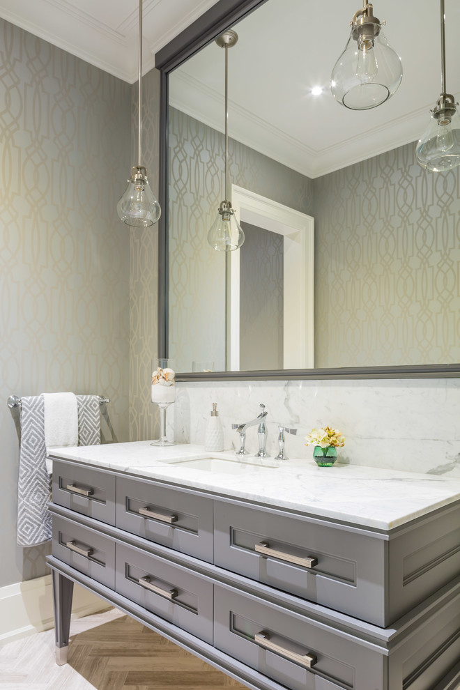 This is an example of a transitional powder room in Toronto with an undermount sink, furniture-like cabinets, grey cabinets, grey walls and white benchtops.
