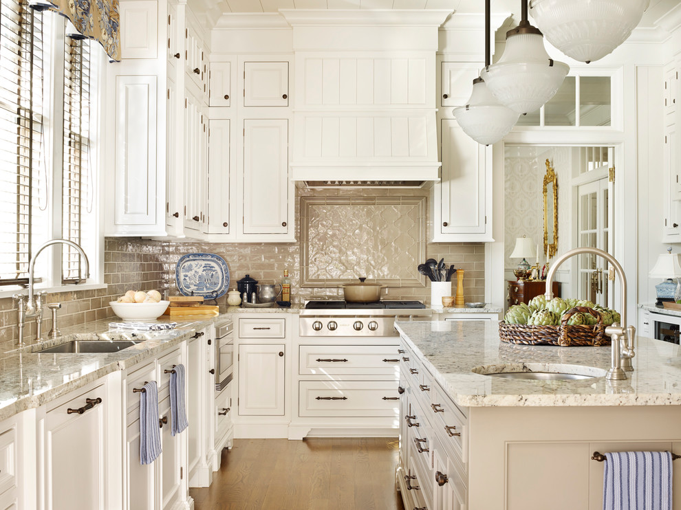 Inspiration for a mid-sized traditional l-shaped open plan kitchen in Atlanta with an undermount sink, white cabinets, beige splashback, with island, beaded inset cabinets, granite benchtops, porcelain splashback, panelled appliances and light hardwood floors.
