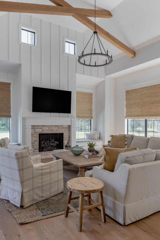 Photo of a large rural open plan games room in Houston with white walls, medium hardwood flooring, a standard fireplace, a brick fireplace surround, a wall mounted tv, brown floors, a vaulted ceiling and wood walls.