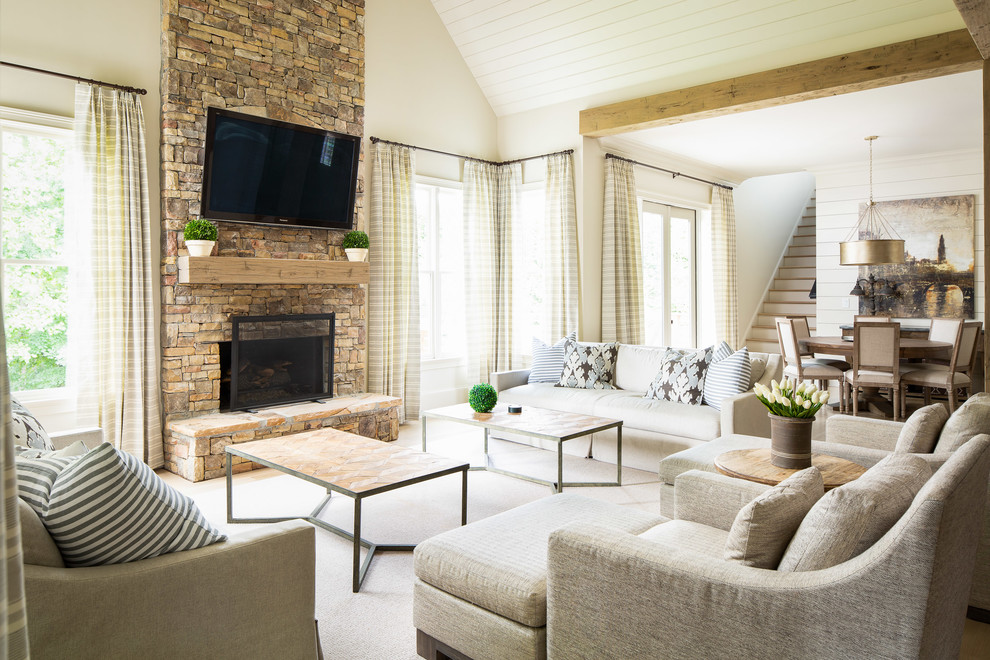 This is an example of a large country open concept living room in Atlanta with a standard fireplace, a stone fireplace surround, a wall-mounted tv and white walls.