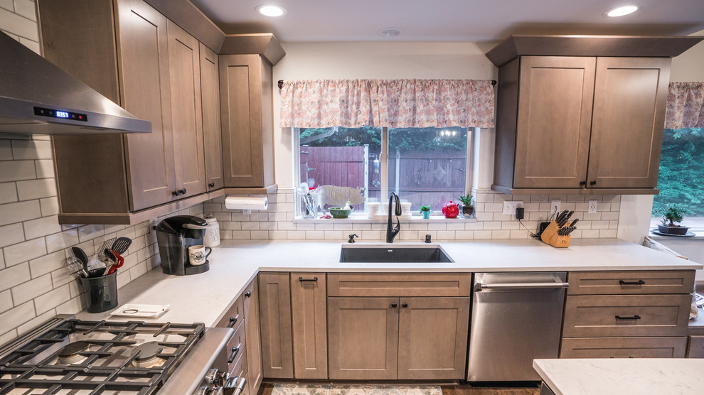 Example of a large transitional l-shaped vinyl floor and brown floor open concept kitchen design in Seattle with an undermount sink, recessed-panel cabinets, medium tone wood cabinets, quartz countertops, white backsplash, subway tile backsplash, stainless steel appliances, an island and white countertops