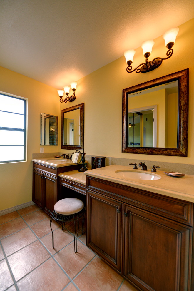 Photo of a mediterranean master bathroom in San Diego with recessed-panel cabinets, medium wood cabinets, an alcove shower, yellow tile, yellow walls, terra-cotta floors, an undermount sink, engineered quartz benchtops, pink floor, a hinged shower door and beige benchtops.