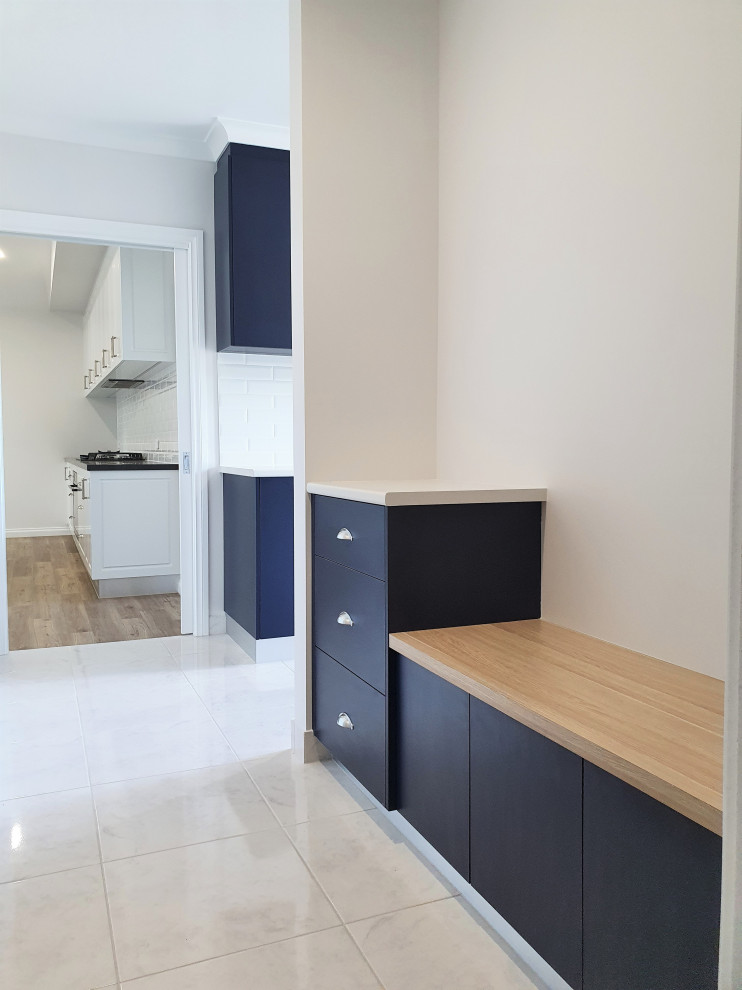 Design ideas for a mid-sized contemporary single-wall dedicated laundry room in Other with a drop-in sink, flat-panel cabinets, blue cabinets, laminate benchtops, white splashback, subway tile splashback, white walls, ceramic floors, a stacked washer and dryer, white floor and white benchtop.