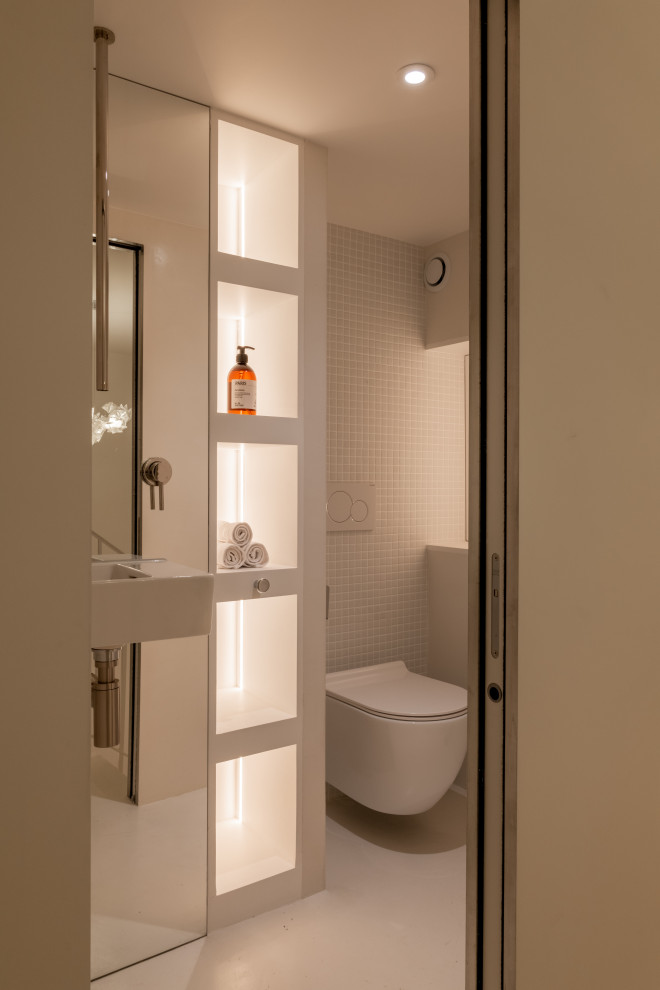 Inspiration for a medium sized contemporary cloakroom in Paris with open cabinets, white cabinets, a wall mounted toilet, white tiles, mosaic tiles, white walls, concrete flooring, a wall-mounted sink, white floors, white worktops and a built in vanity unit.