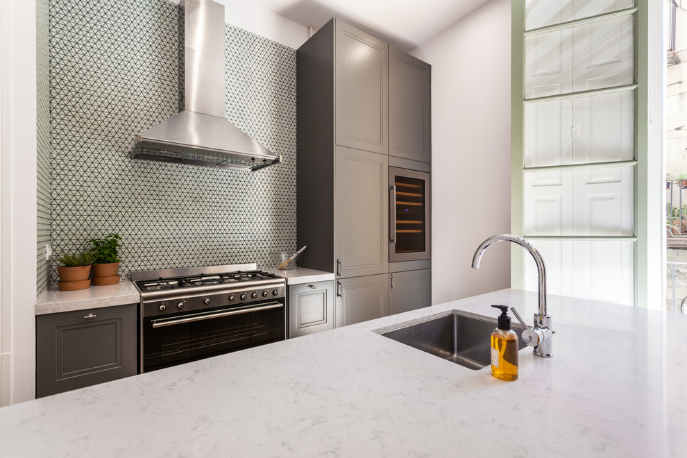 Design ideas for a mid-sized contemporary single-wall open plan kitchen in Barcelona with recessed-panel cabinets, grey cabinets, marble benchtops, multi-coloured splashback, mosaic tile splashback, medium hardwood floors, with island and beige floor.