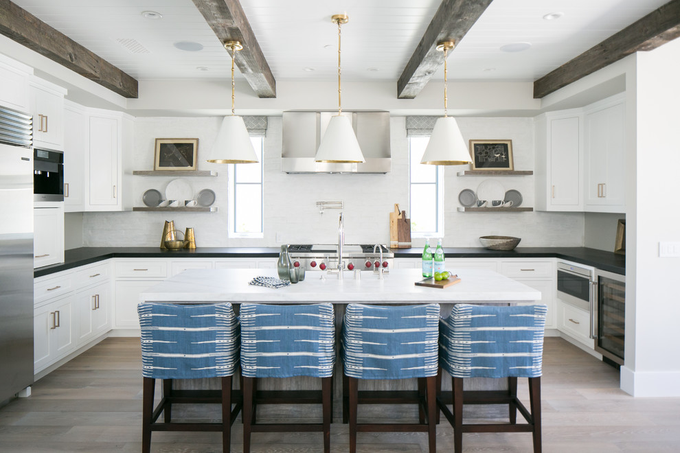 Transitional u-shaped kitchen photo in Orange County with shaker cabinets, white backsplash, stainless steel appliances and an island