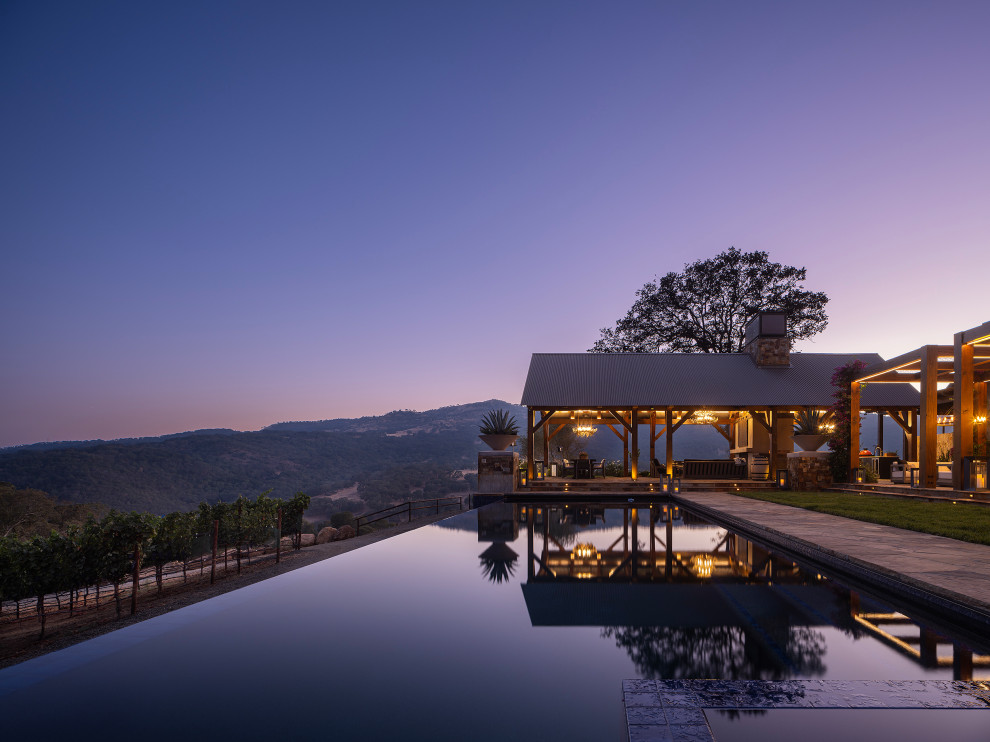 Diseño de casa de la piscina y piscina infinita campestre grande rectangular en patio lateral con adoquines de piedra natural