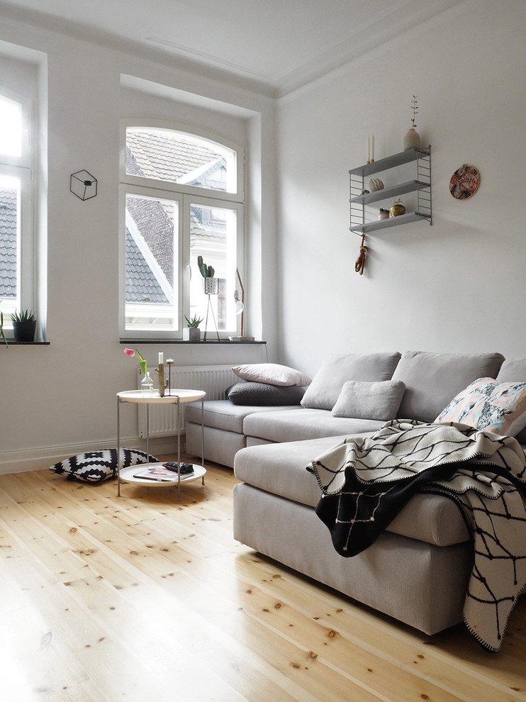 This is an example of a small scandinavian enclosed family room in Cologne with white walls, light hardwood floors and no fireplace.