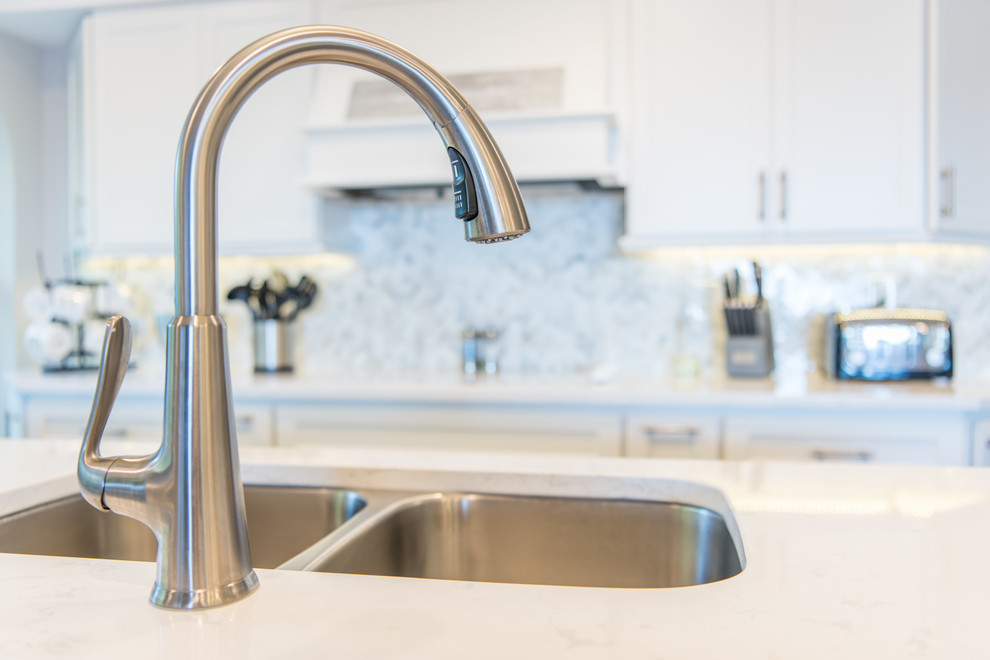Inspiration for a large transitional u-shaped porcelain tile and brown floor eat-in kitchen remodel with an undermount sink, shaker cabinets, white cabinets, quartz countertops, white backsplash, marble backsplash, stainless steel appliances and two islands