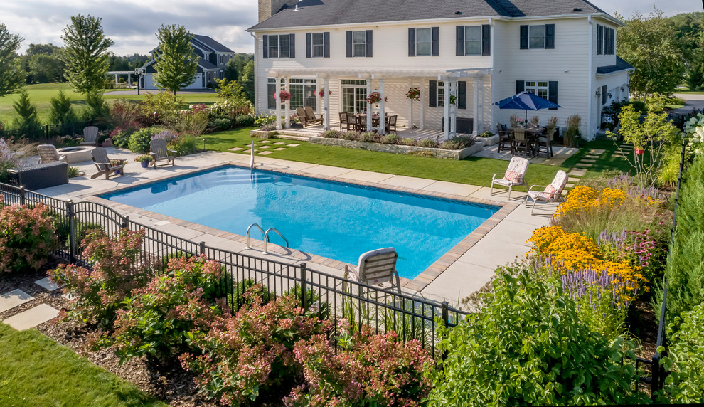 Large traditional backyard rectangular pool in Milwaukee with concrete slab.