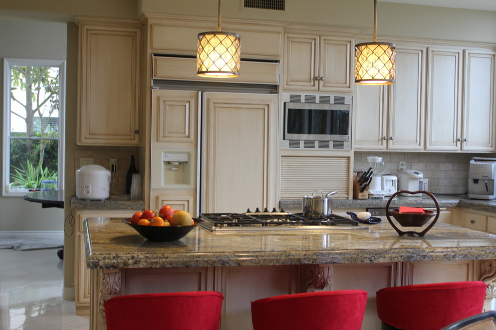 Example of a large transitional u-shaped ceramic tile and beige floor enclosed kitchen design in Orange County with recessed-panel cabinets, beige cabinets, granite countertops, beige backsplash, stone tile backsplash, paneled appliances, an island, an undermount sink and beige countertops