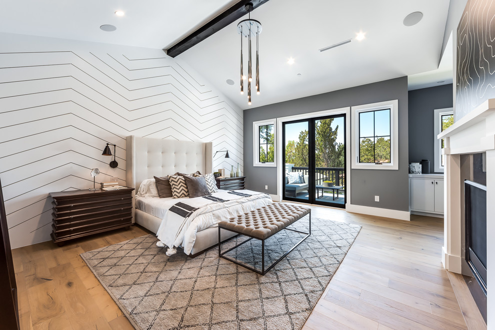 Design ideas for a transitional bedroom in Los Angeles with grey walls, medium hardwood floors, a standard fireplace and brown floor.