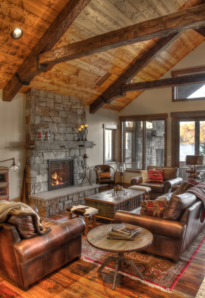 Inspiration for a country open concept family room in Minneapolis with beige walls, medium hardwood floors, a standard fireplace and a stone fireplace surround.