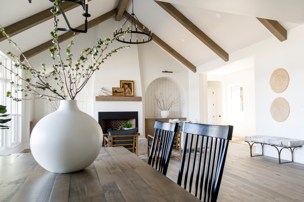 Mittelgroßes Landhausstil Wohnzimmer mit weißer Wandfarbe, braunem Holzboden, Kamin, verputzter Kaminumrandung, gewölbter Decke und Holzdielenwänden in Boise
