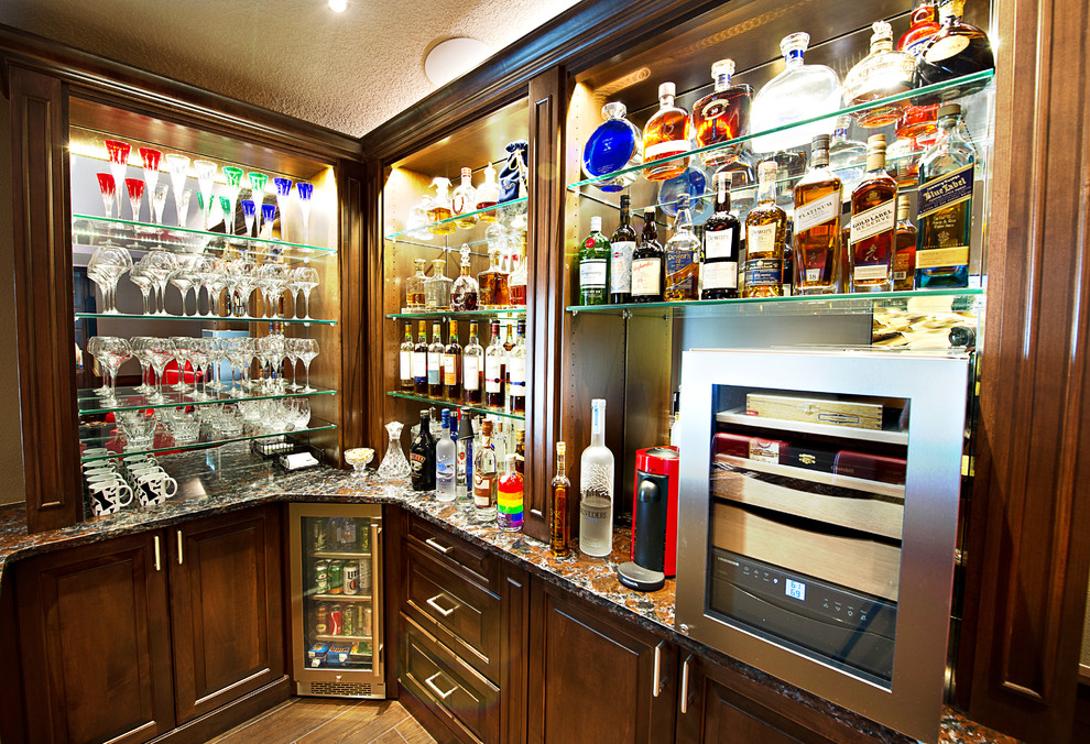 This is an example of a mid-sized traditional l-shaped seated home bar in Tampa with raised-panel cabinets, brown cabinets, quartz benchtops, mirror splashback, porcelain floors, brown floor and multi-coloured benchtop.