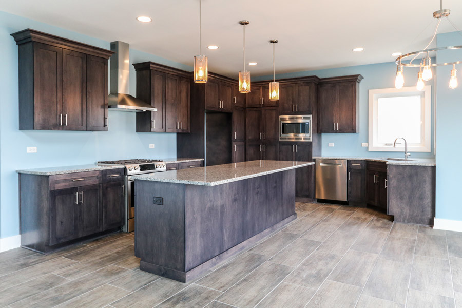 This is an example of a mid-sized country u-shaped eat-in kitchen in Chicago with an undermount sink, granite benchtops, stainless steel appliances, ceramic floors, with island and grey floor.