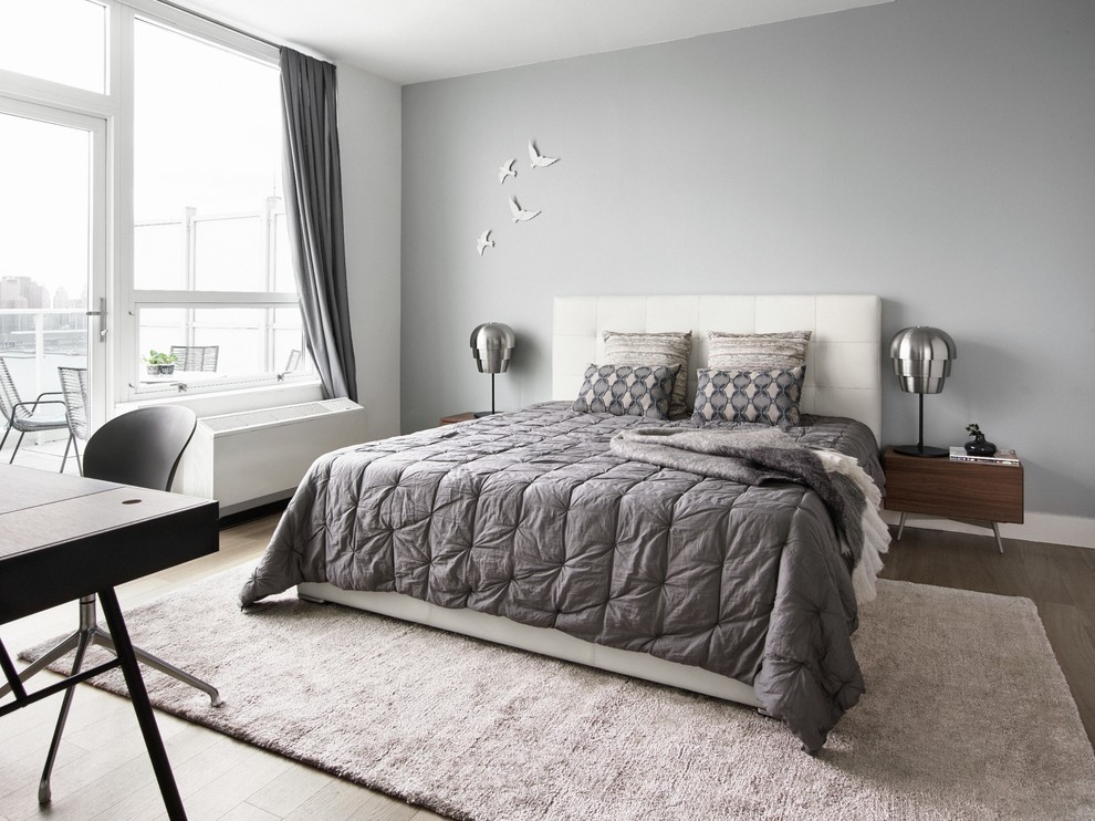 Photo of a large contemporary master bedroom in Manchester with grey walls and plywood floors.
