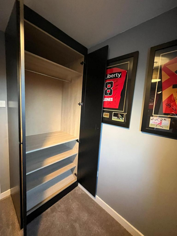 Idée de décoration pour une petite armoire encastrée minimaliste neutre avec un placard à porte shaker, des portes de placard noires, moquette et un sol beige.
