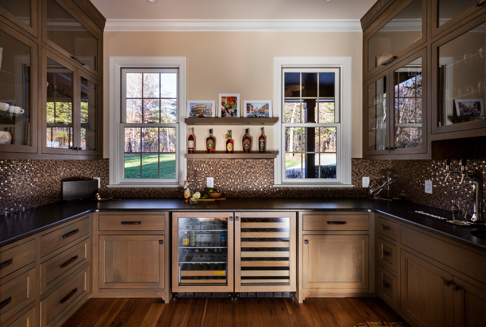 This is an example of an expansive country kitchen pantry in Charlotte with an integrated sink, flat-panel cabinets, medium wood cabinets, onyx benchtops, glass tile splashback, panelled appliances, medium hardwood floors, no island and black benchtop.