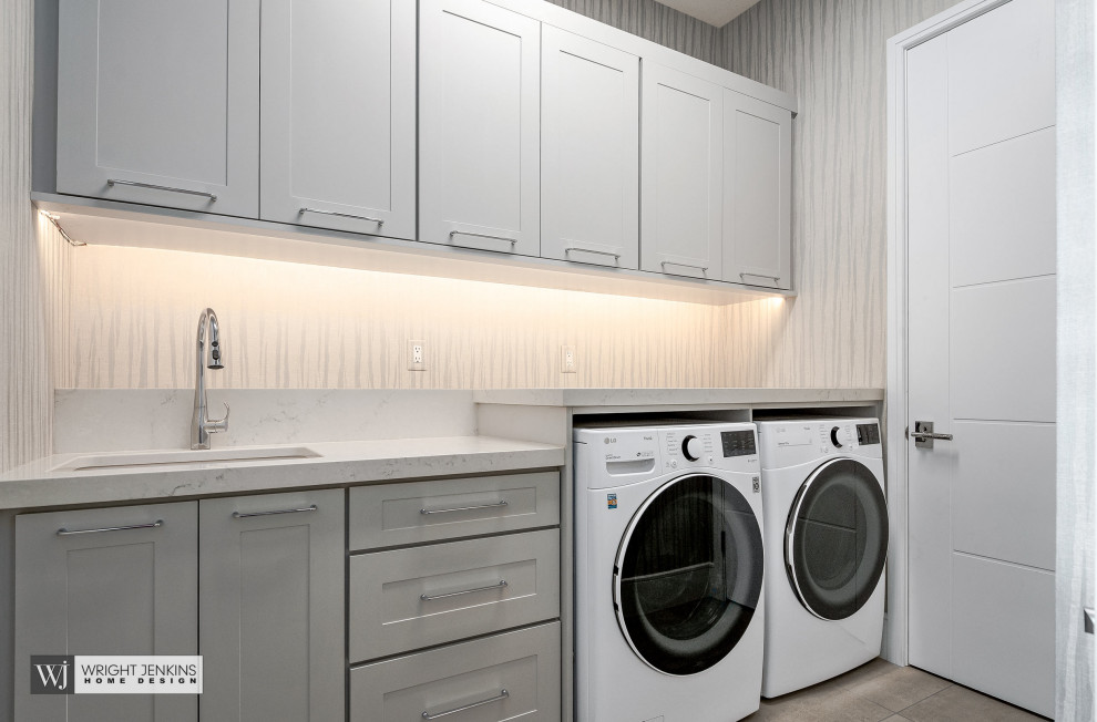 Inspiration for a mid-sized transitional galley dedicated laundry room in Other with an undermount sink, recessed-panel cabinets, grey cabinets, quartzite benchtops, beige walls, ceramic floors, a side-by-side washer and dryer, grey floor and beige benchtop.