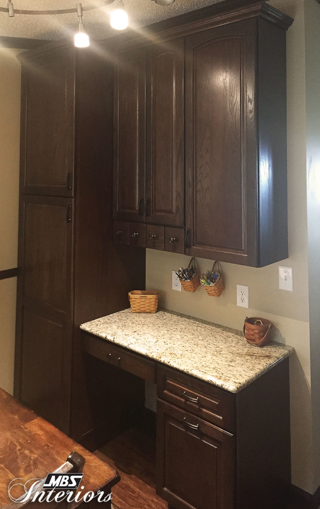 Inspiration for a small transitional u-shaped medium tone wood floor enclosed kitchen remodel with an undermount sink, dark wood cabinets, gray backsplash, stone tile backsplash, stainless steel appliances and no island