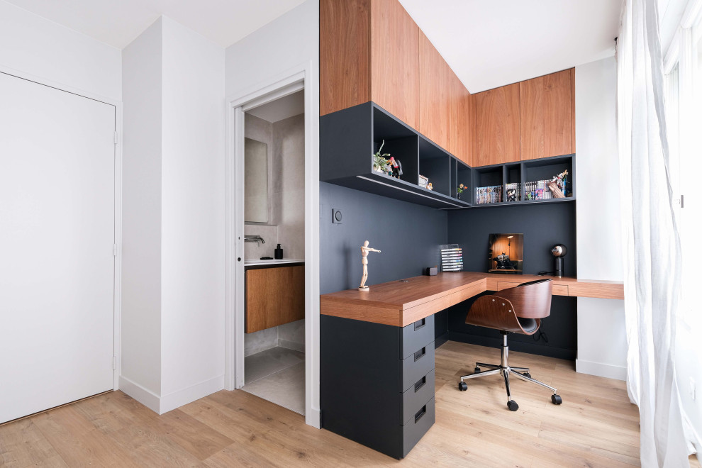 Cette photo montre un bureau tendance de taille moyenne avec un mur noir, parquet clair, un bureau intégré et un sol marron.