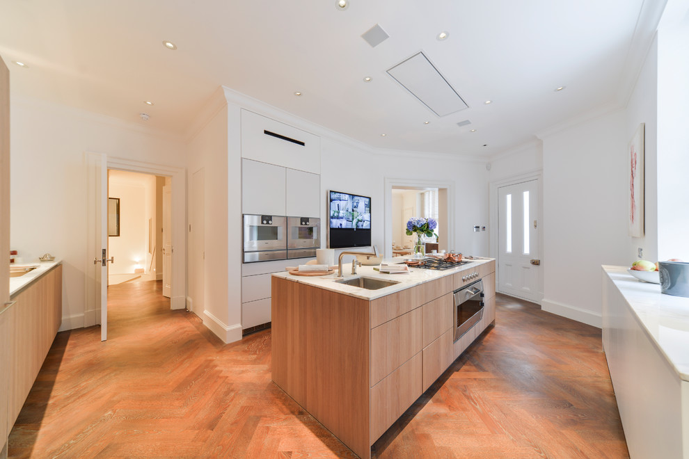 Photo of a mid-sized contemporary l-shaped kitchen in London with an undermount sink, flat-panel cabinets, medium wood cabinets, white splashback, stainless steel appliances, medium hardwood floors, with island, brown floor, white benchtop, marble benchtops and marble splashback.