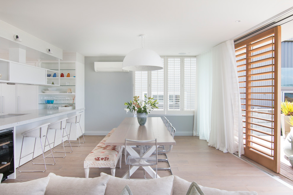 Photo of a mid-sized beach style separate dining room in Auckland with blue walls, medium hardwood floors and beige floor.