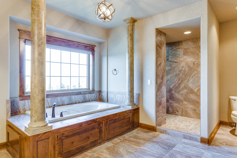 Large mountain style master drop-in bathtub photo with shaker cabinets and medium tone wood cabinets