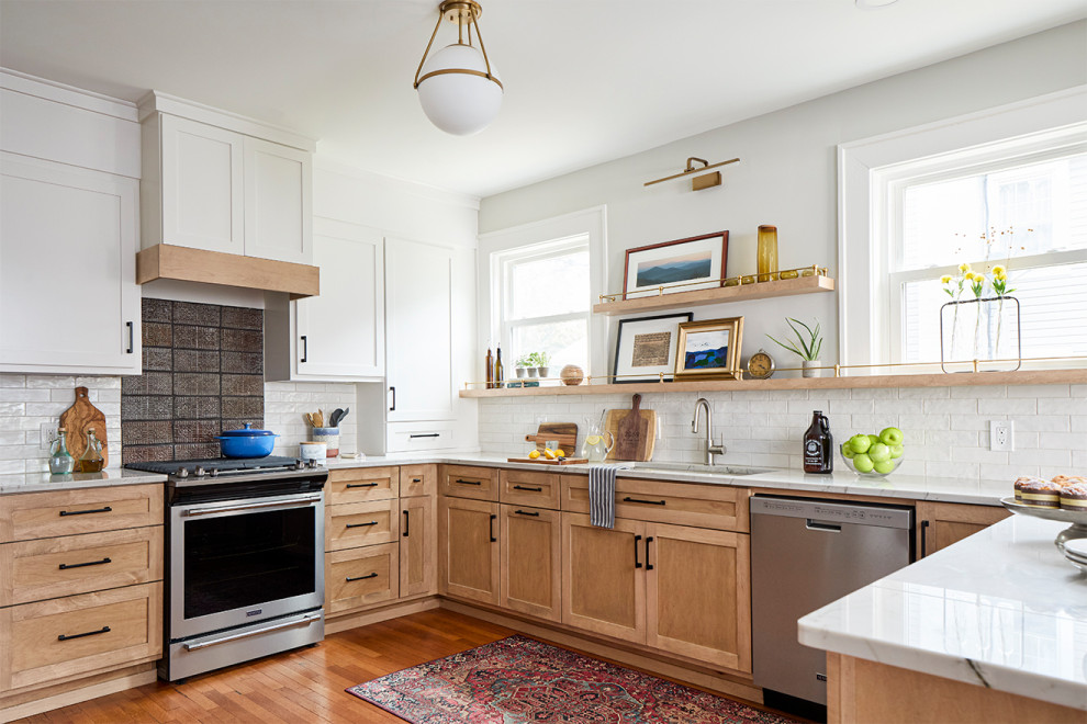 Immagine di un grande cucina con isola centrale chic con ante in legno chiaro, paraspruzzi bianco, elettrodomestici in acciaio inossidabile, pavimento marrone e top bianco