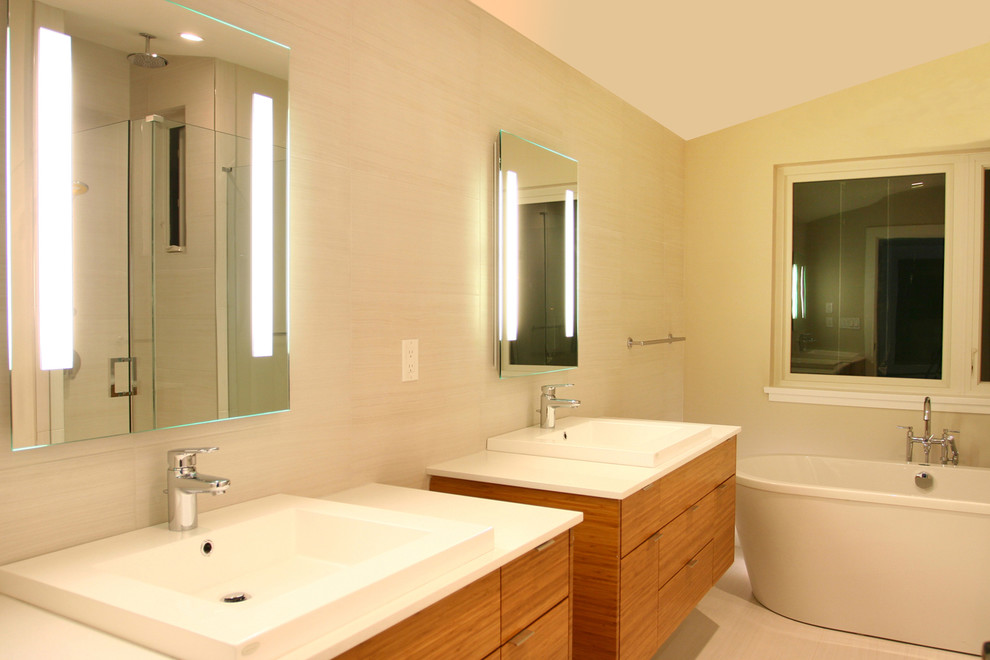 Inspiration for a large contemporary master bathroom in Vancouver with a drop-in sink, flat-panel cabinets, light wood cabinets, engineered quartz benchtops, a freestanding tub, an alcove shower, a one-piece toilet, beige tile, ceramic tile, beige walls and ceramic floors.