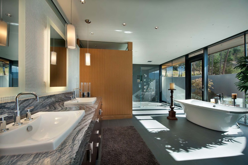 This is an example of a large contemporary master bathroom in Vancouver with a vessel sink, furniture-like cabinets, dark wood cabinets, marble benchtops, a hot tub, a curbless shower, a one-piece toilet and stone slab.