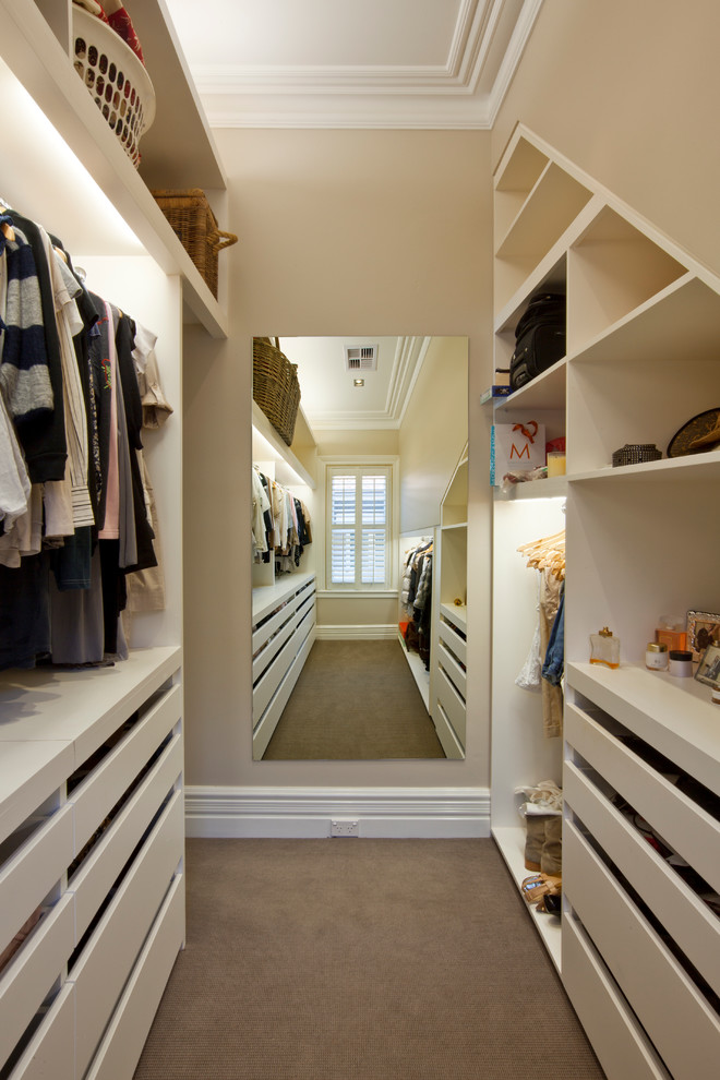 Large transitional gender-neutral walk-in wardrobe in Sydney with flat-panel cabinets, white cabinets and carpet.