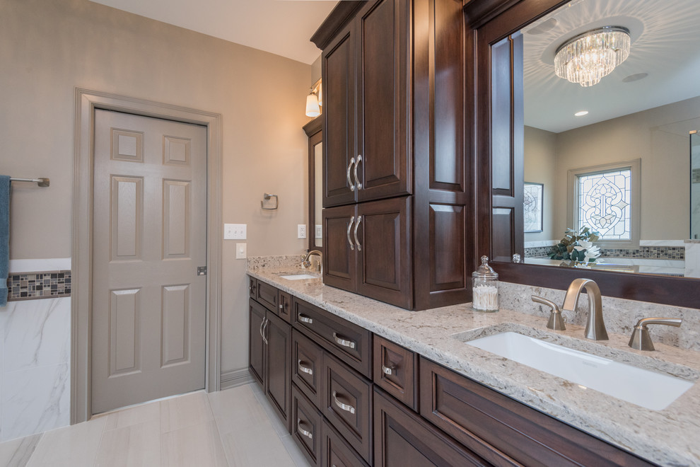 Large transitional master bathroom in Louisville with raised-panel cabinets, dark wood cabinets, a freestanding tub, a corner shower, white tile, marble, beige walls, porcelain floors, an undermount sink, engineered quartz benchtops, beige floor and a hinged shower door.