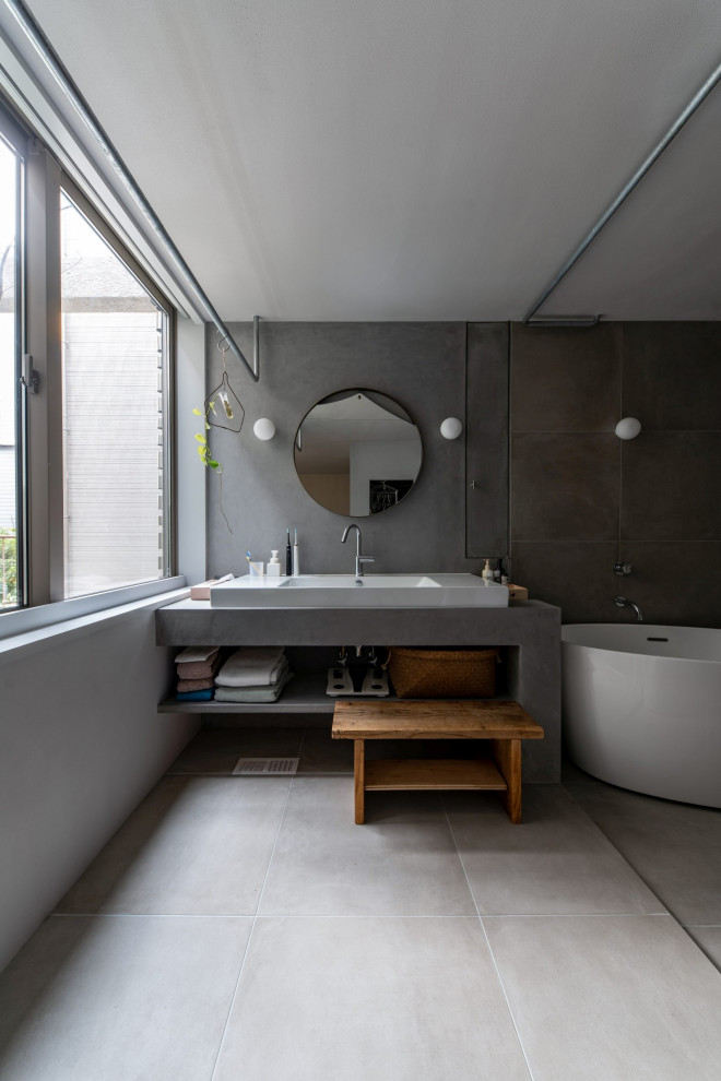 Exempel på ett litet minimalistiskt grå grått toalett, med öppna hyllor, vita skåp, grå kakel, porslinskakel, grå väggar, klinkergolv i porslin, ett nedsänkt handfat och grått golv