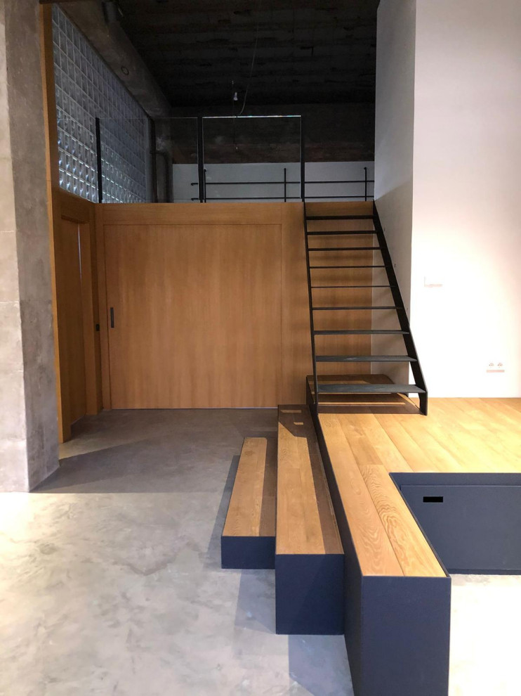 На фото: прямая лестница в стиле лофт с металлическими ступенями и панелями на части стены без подступенок