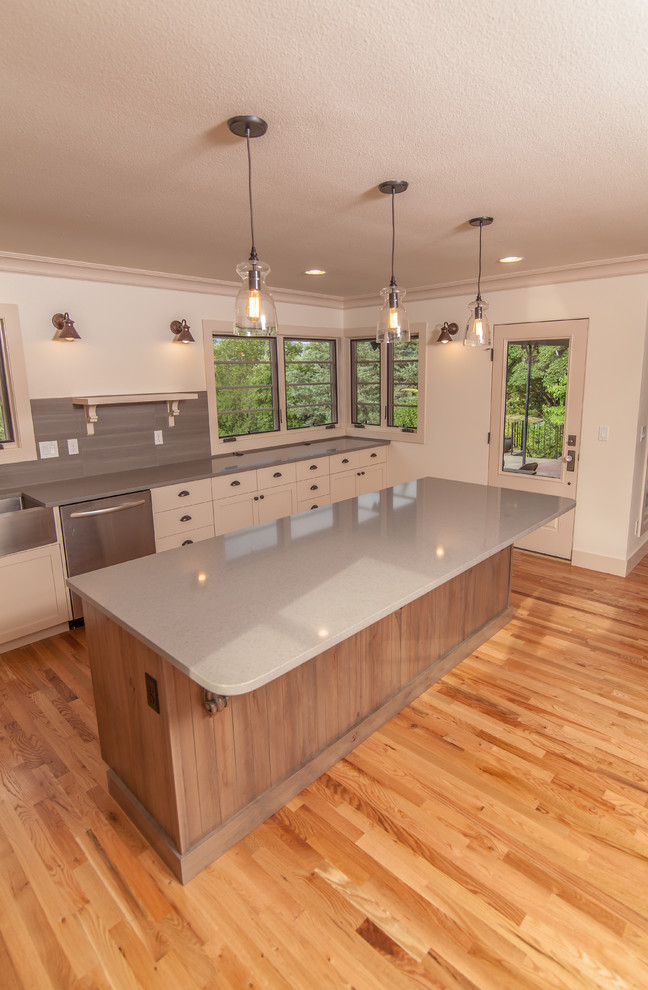 Design ideas for a large contemporary l-shaped eat-in kitchen in Boise with a single-bowl sink, shaker cabinets, white cabinets, quartz benchtops, grey splashback, ceramic splashback, stainless steel appliances, light hardwood floors and with island.