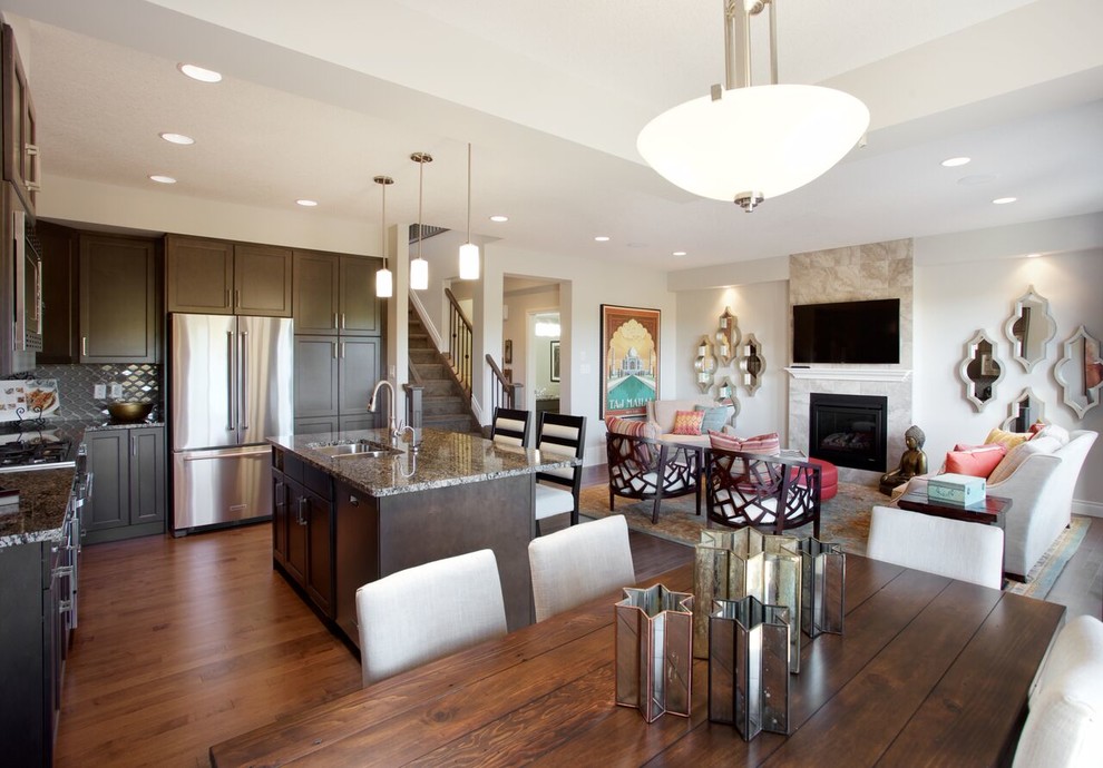 Open concept kitchen - large transitional l-shaped dark wood floor and brown floor open concept kitchen idea in Edmonton with a double-bowl sink, raised-panel cabinets, dark wood cabinets, granite countertops, gray backsplash, glass tile backsplash, stainless steel appliances and an island
