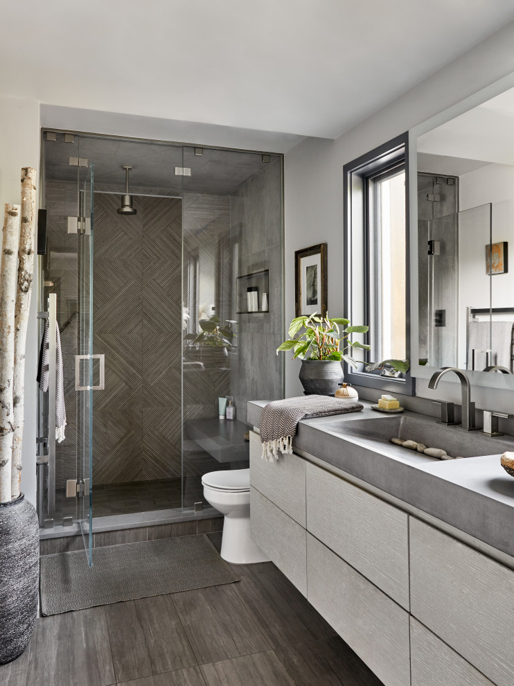 This is an example of a scandinavian bathroom in New York with flat-panel cabinets, grey cabinets, an alcove shower, gray tile, grey walls, an integrated sink, grey floor, a hinged shower door, grey benchtops, a single vanity and a floating vanity.