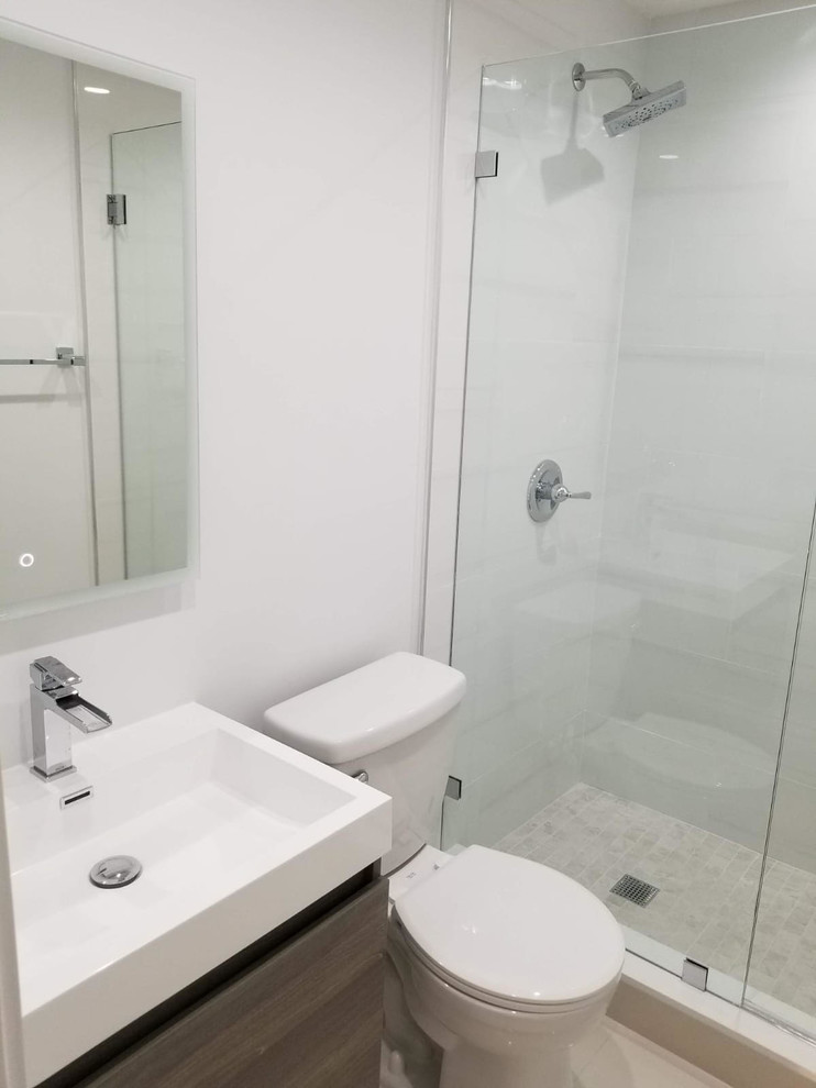 Alcove shower - small contemporary 3/4 white tile and porcelain tile porcelain tile and white floor alcove shower idea in Miami with flat-panel cabinets, light wood cabinets, a two-piece toilet, white walls, an integrated sink, solid surface countertops, a hinged shower door and white countertops