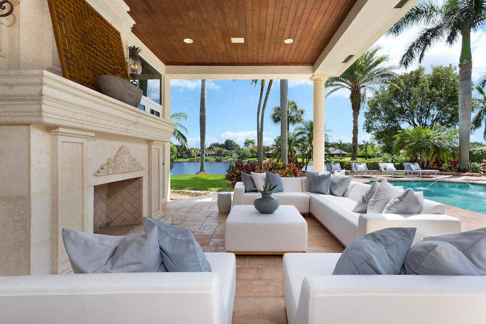 Photo of a mediterranean patio in Miami with a roof extension and with fireplace.