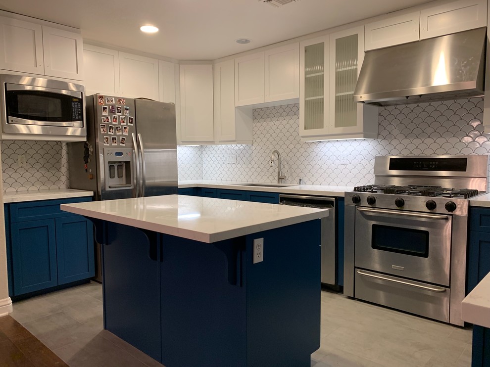 Inspiration for a mid-sized transitional u-shaped kitchen in San Diego with an undermount sink, shaker cabinets, blue cabinets, quartz benchtops, white splashback, ceramic splashback, stainless steel appliances, cement tiles, with island, grey floor and white benchtop.