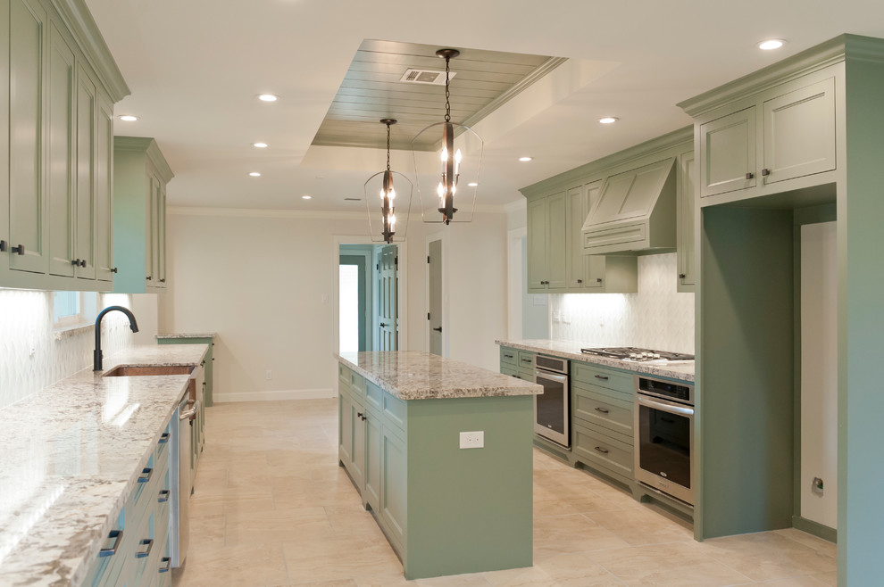Design ideas for a large tropical galley kitchen in Houston with a farmhouse sink, recessed-panel cabinets, green cabinets, granite benchtops, white splashback, glass tile splashback, stainless steel appliances, porcelain floors and with island.