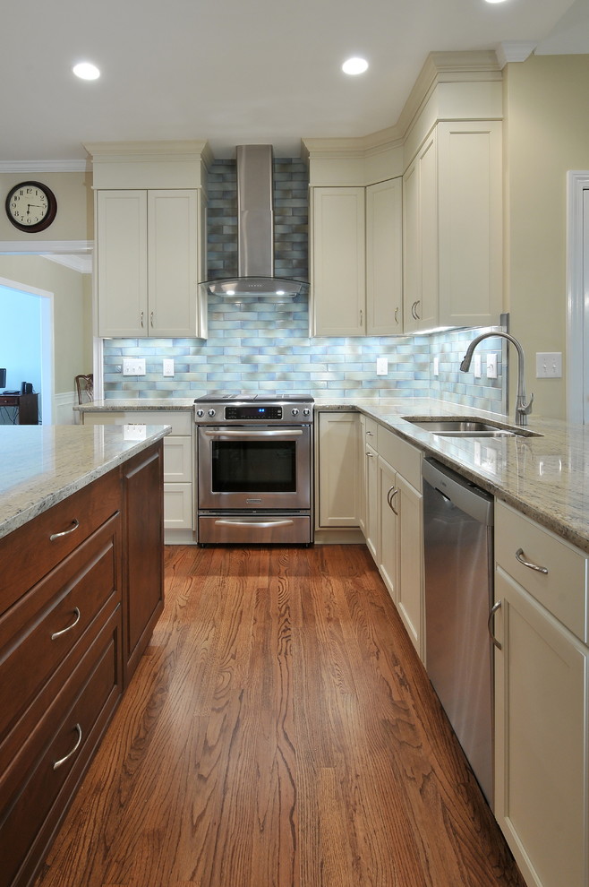 Photo of a traditional kitchen in Atlanta with a double-bowl sink, recessed-panel cabinets, white cabinets, blue splashback, subway tile splashback and stainless steel appliances.