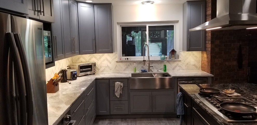 Design ideas for a mid-sized l-shaped eat-in kitchen in Other with a farmhouse sink, shaker cabinets, grey cabinets, granite benchtops, stone tile splashback, stainless steel appliances, laminate floors, with island, grey floor and multi-coloured benchtop.