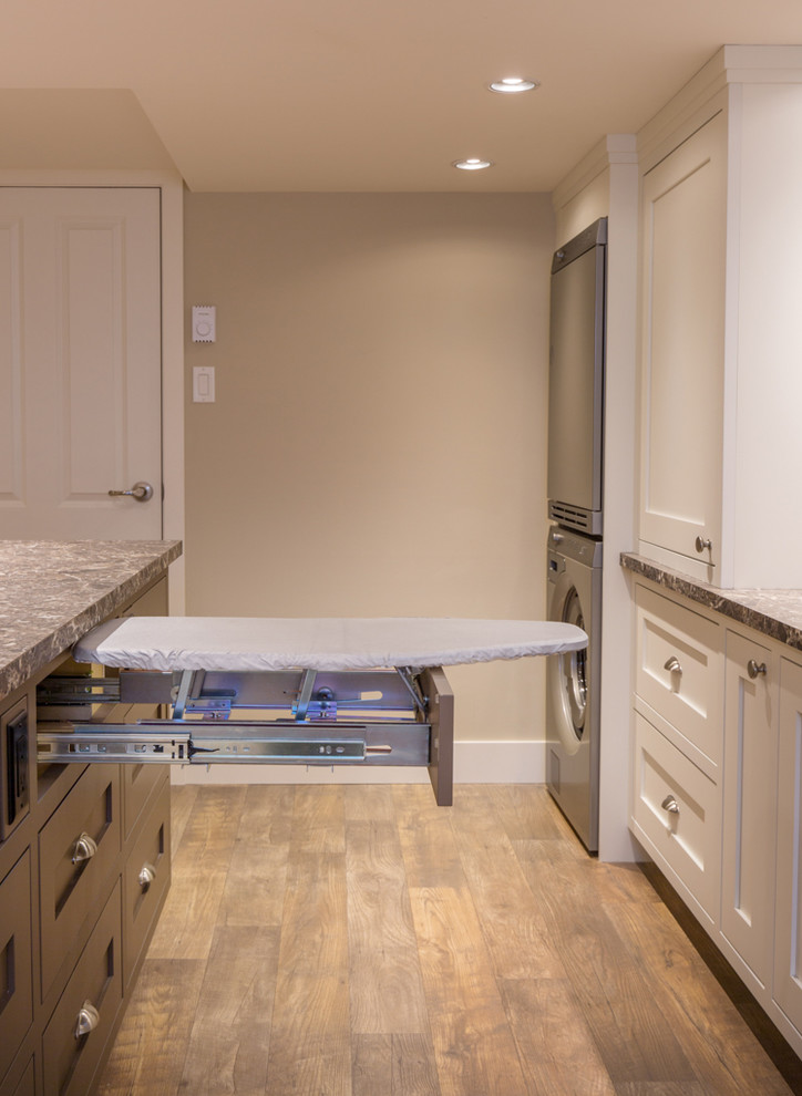 Mid-sized transitional single-wall utility room in Other with a single-bowl sink, shaker cabinets, white cabinets, laminate benchtops, beige walls, vinyl floors, a stacked washer and dryer and beige floor.