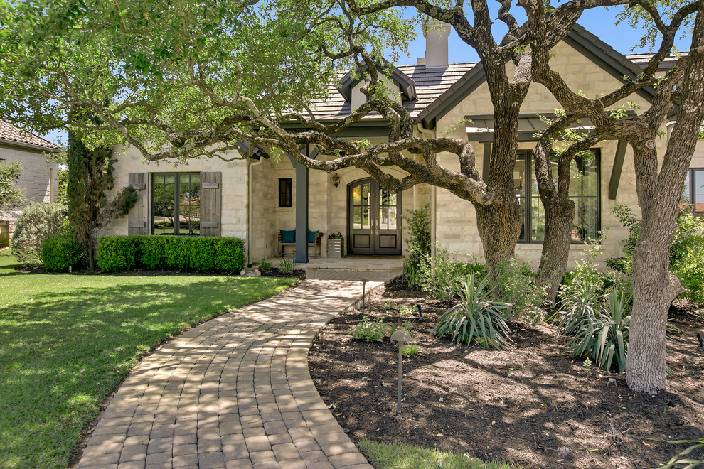 Inspiration for an expansive transitional two-storey beige house exterior in Austin with stone veneer, a gable roof and a tile roof.