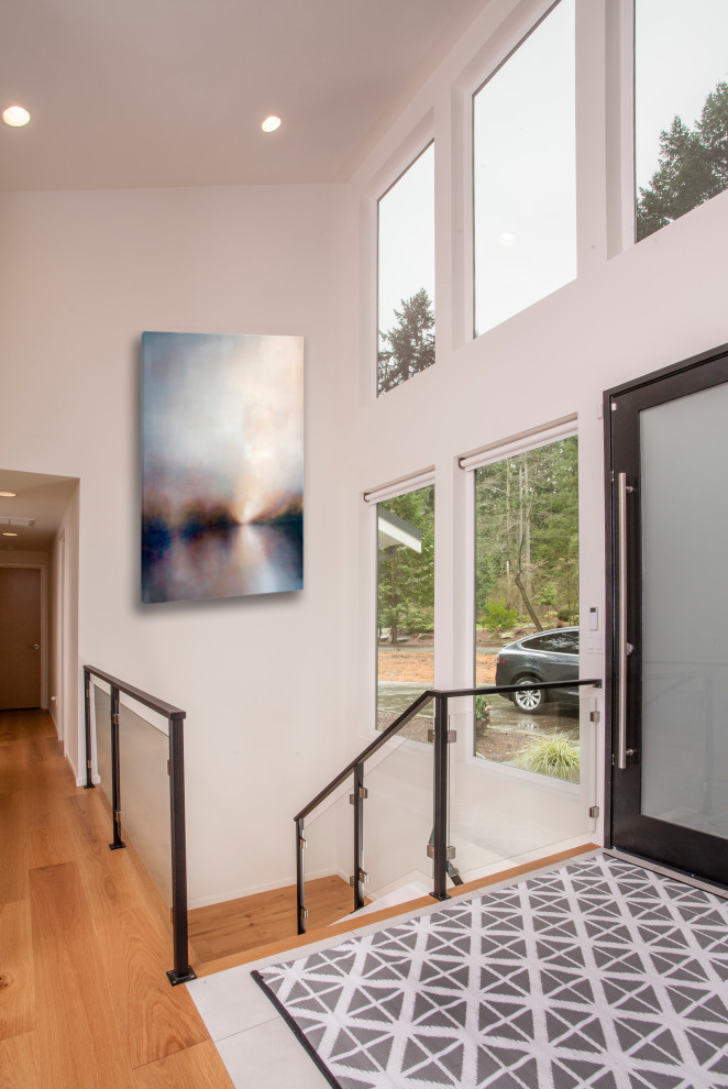 Photo of a large midcentury front door in Seattle with white walls, medium hardwood floors, a single front door, a black front door and brown floor.