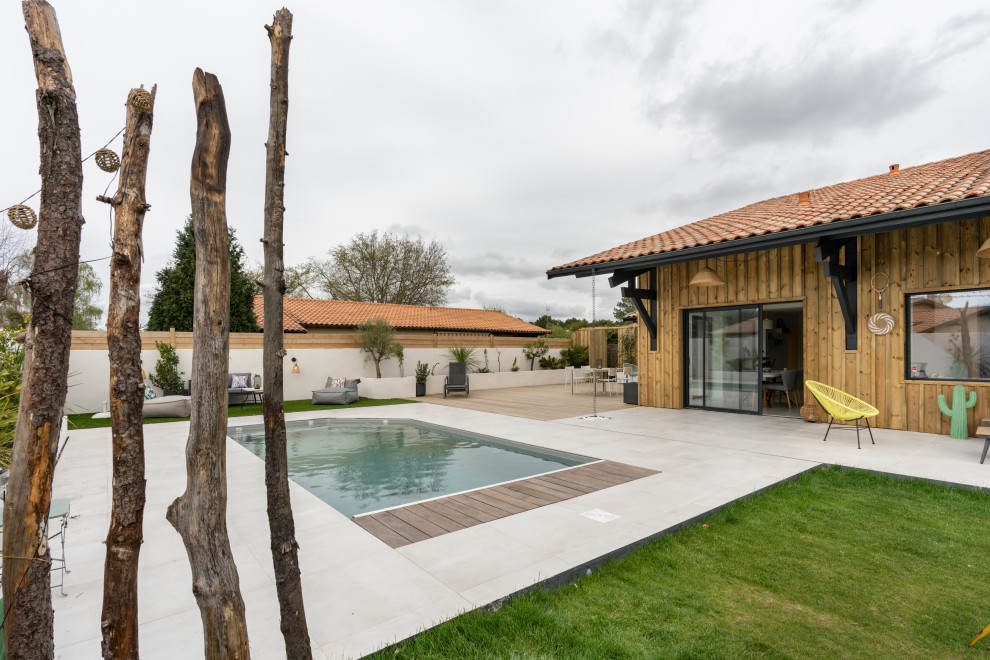 Aménagement d'un grand piscine avec aménagement paysager arrière bord de mer rectangle avec une terrasse en bois.
